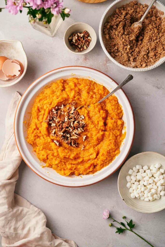 A bowl of sweet potato mashed potatoes with pecans.