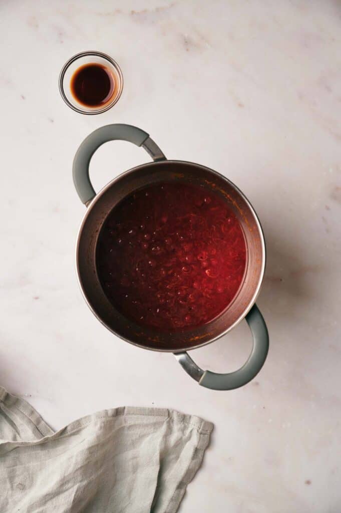 A pot of Cranberry sauce on a marble table.