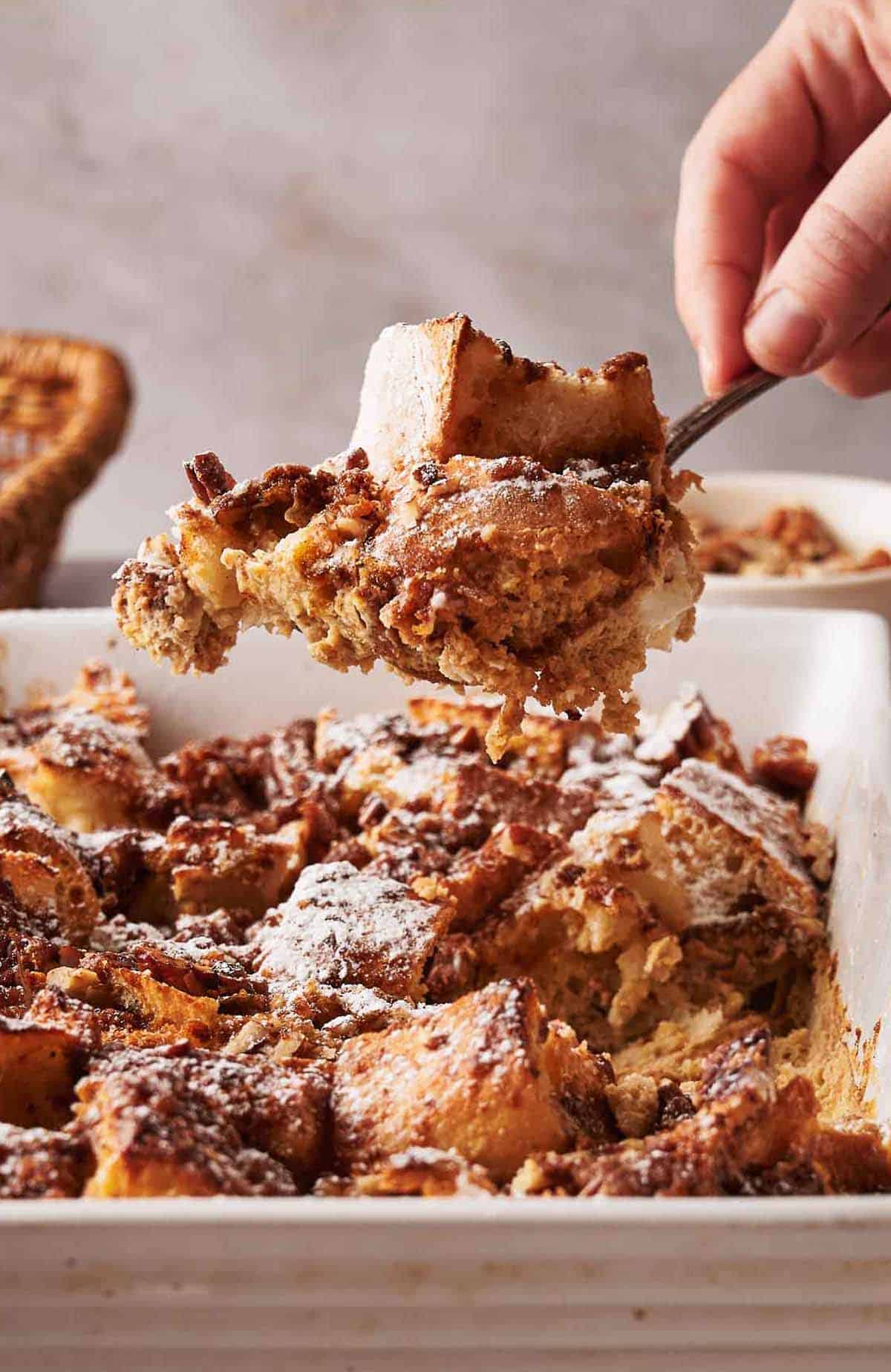 A person taking a piece of French Toast Casserole out of a dish.