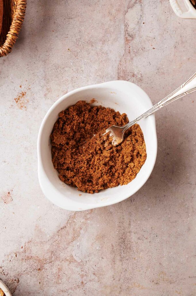 Cinnamon powder in a white bowl with a spoon.