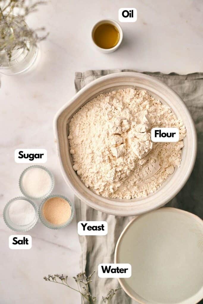 A bowl of flour, oil, and other ingredients on a white table.