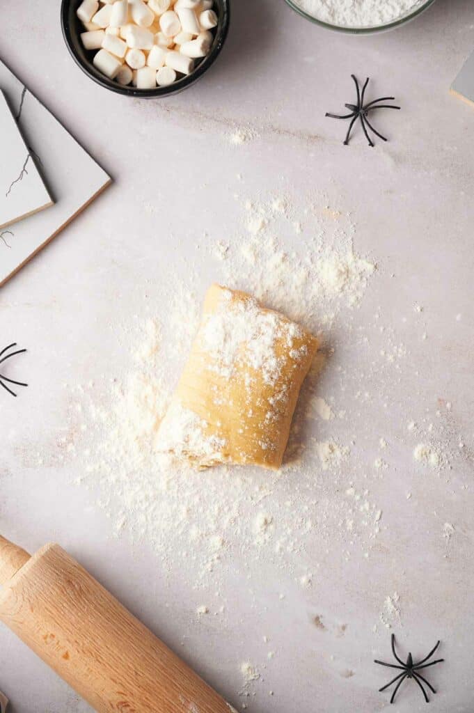 A table with flour, sugar, and a rolling pin next to a spider.