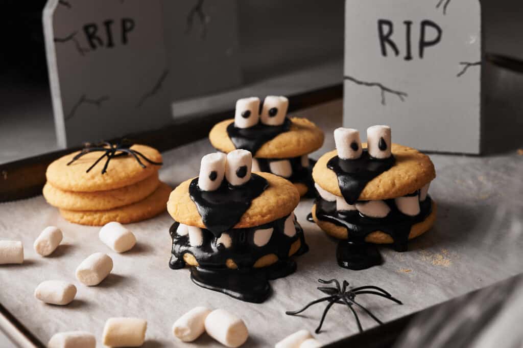 Halloween cookies with marshmallows and ghosts on a tray.