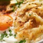 A plate of hash browns with avocado and eggs.