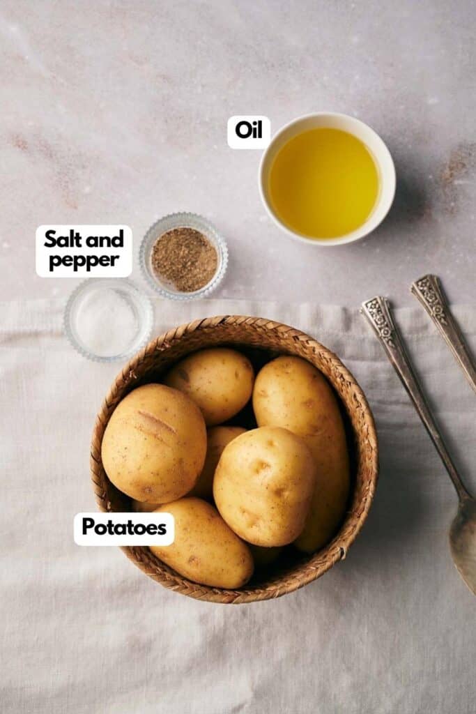 A bowl with potatoes, oil, salt and pepper.