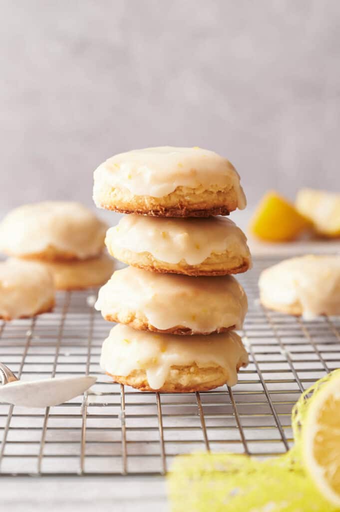 A stack of lemon cookies on a cooling rack with a spoon.