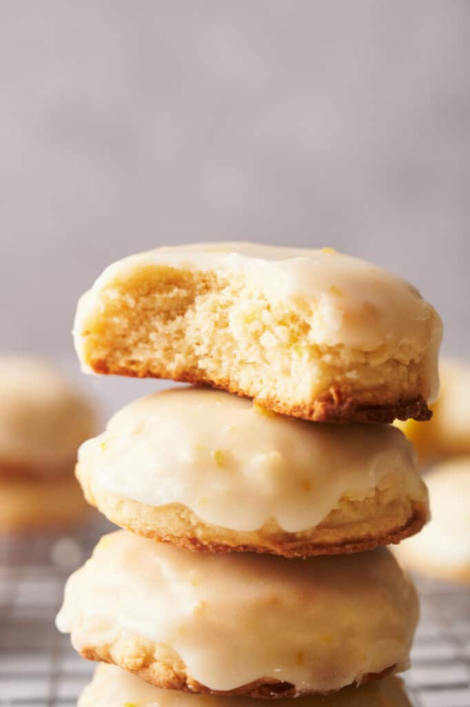 A stack of lemon cookies on a cooling rack, one with a bite out of it.