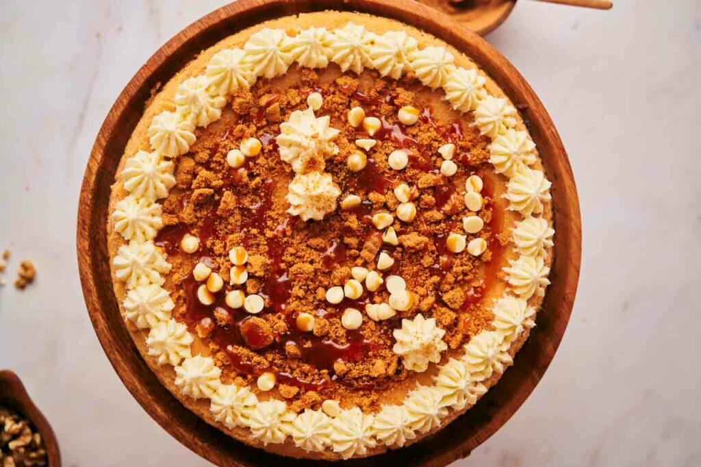 A pumpkin pie with whipped cream, nuts and caramel on a wooden plate.