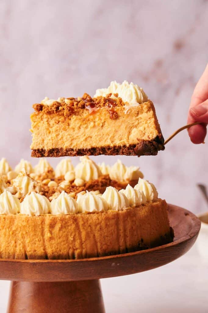 A slice of pumpkin cheesecake on a wooden plate.