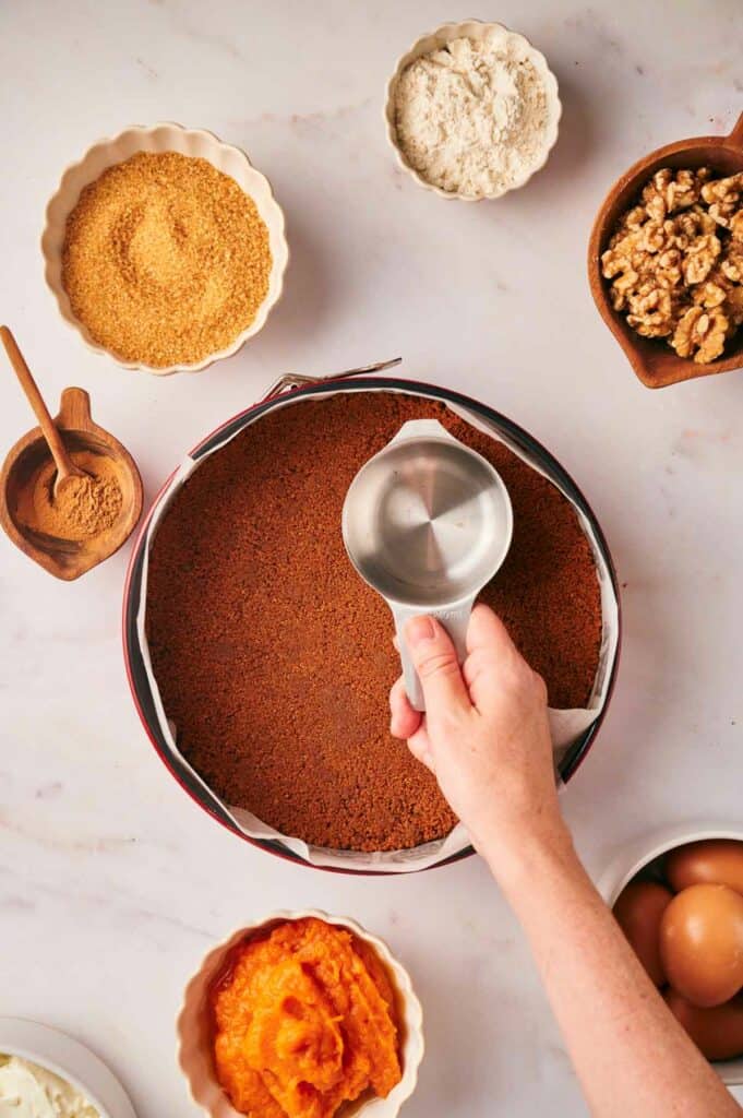 A person is measuring ingredients for a pumpkin pie.