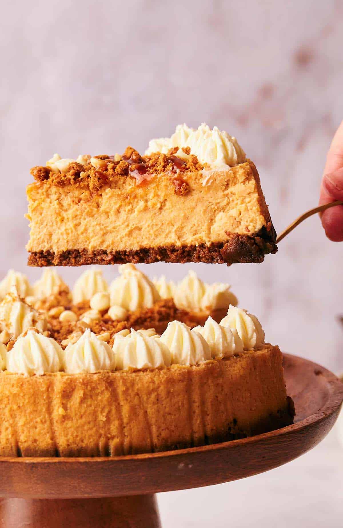 A slice of pumpkin cheesecake on a wooden plate.