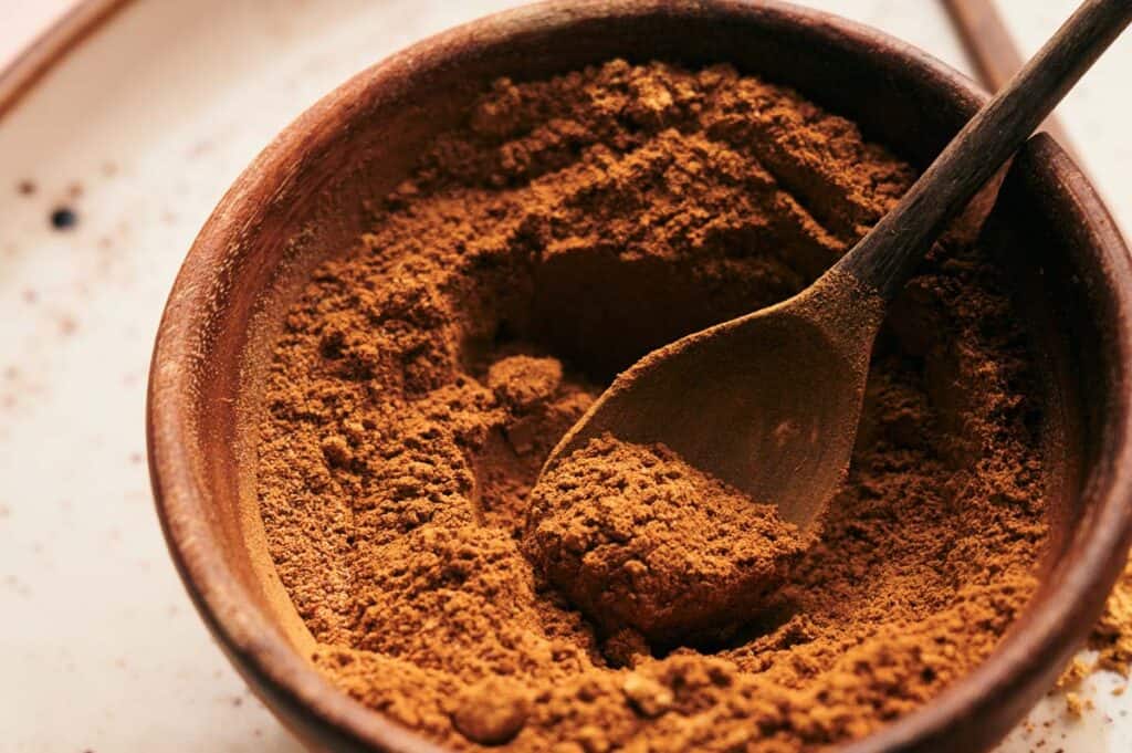 Pumpkin Pie Spice in a bowl with a wooden spoon.