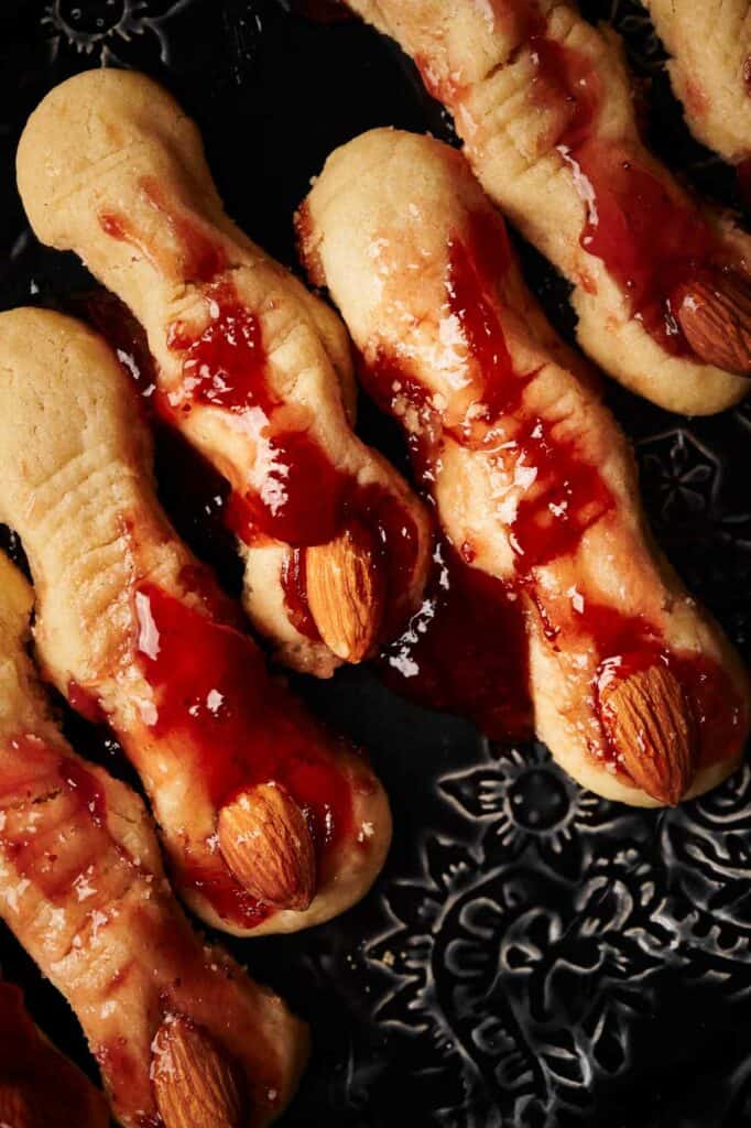 A plate of witch finger cookies with jelly on them.