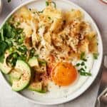 Air fryer hash browns with avocado and eggs on a plate.