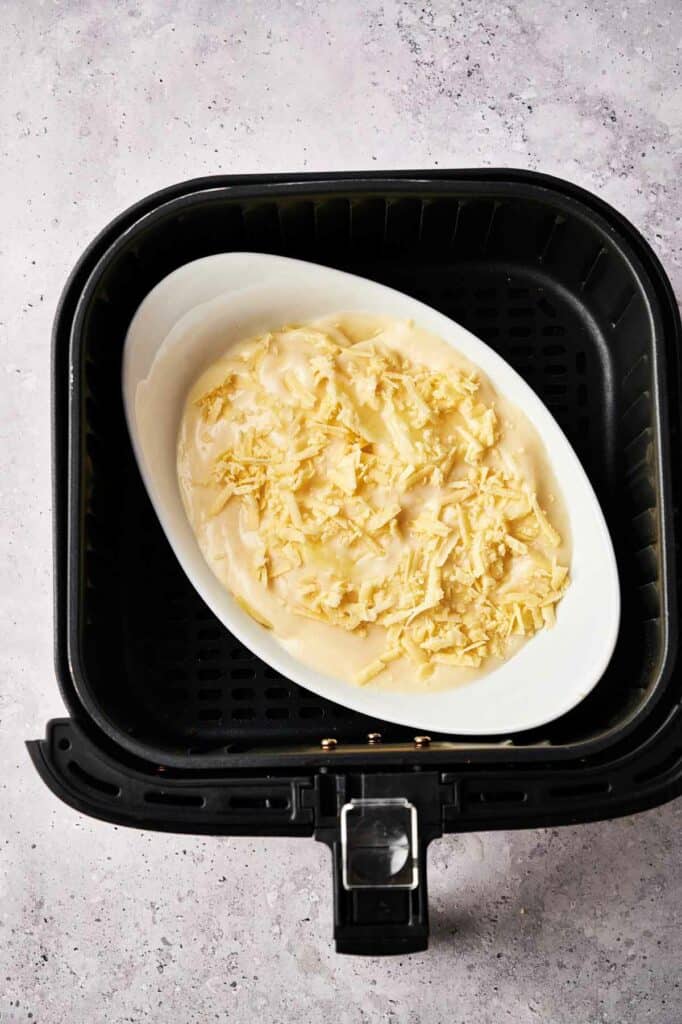 An air fryer with a bowl of cheesy potatoes in it.