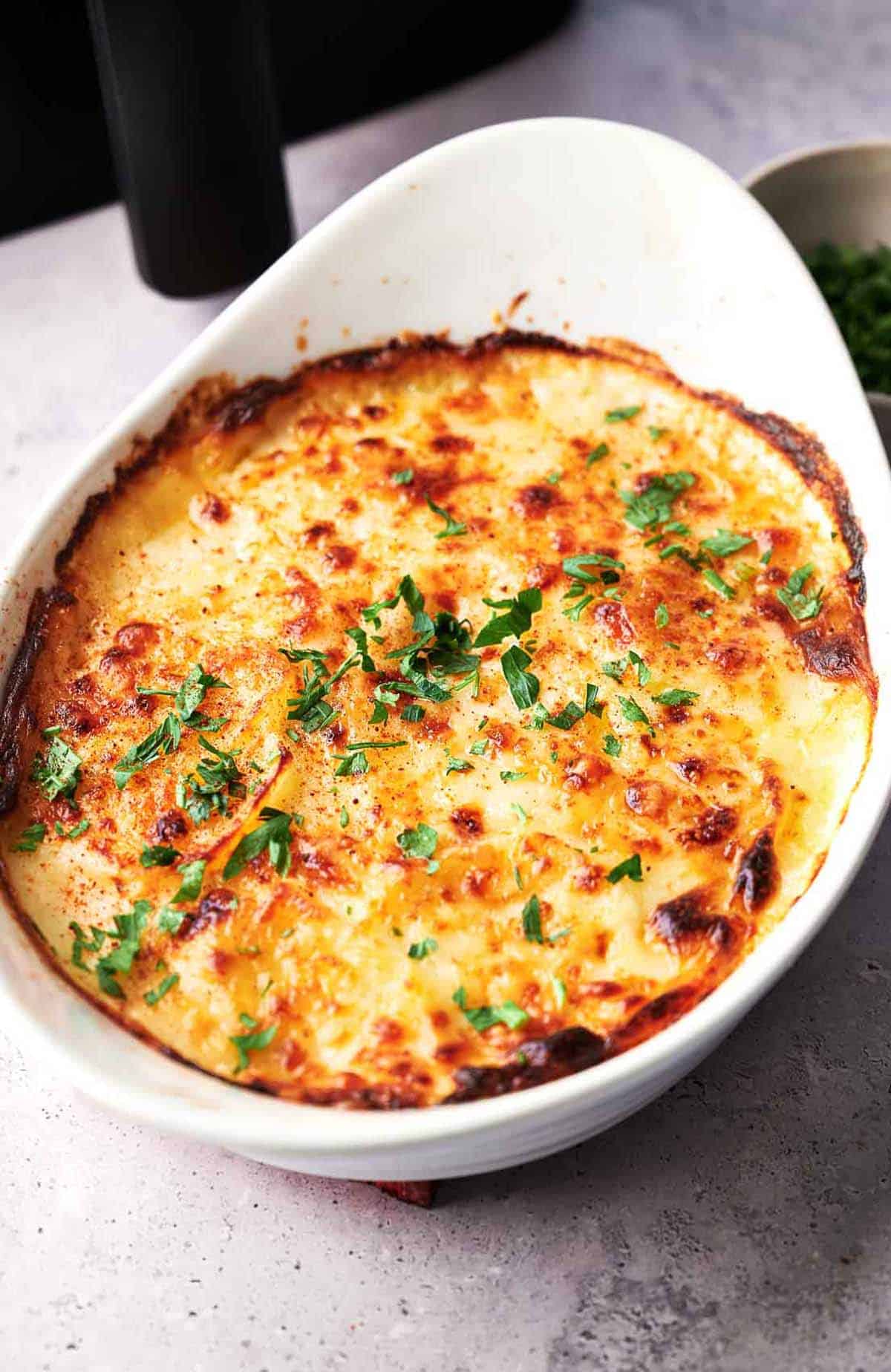 Scalloped potatoes in a baking dish next to an air fryer.