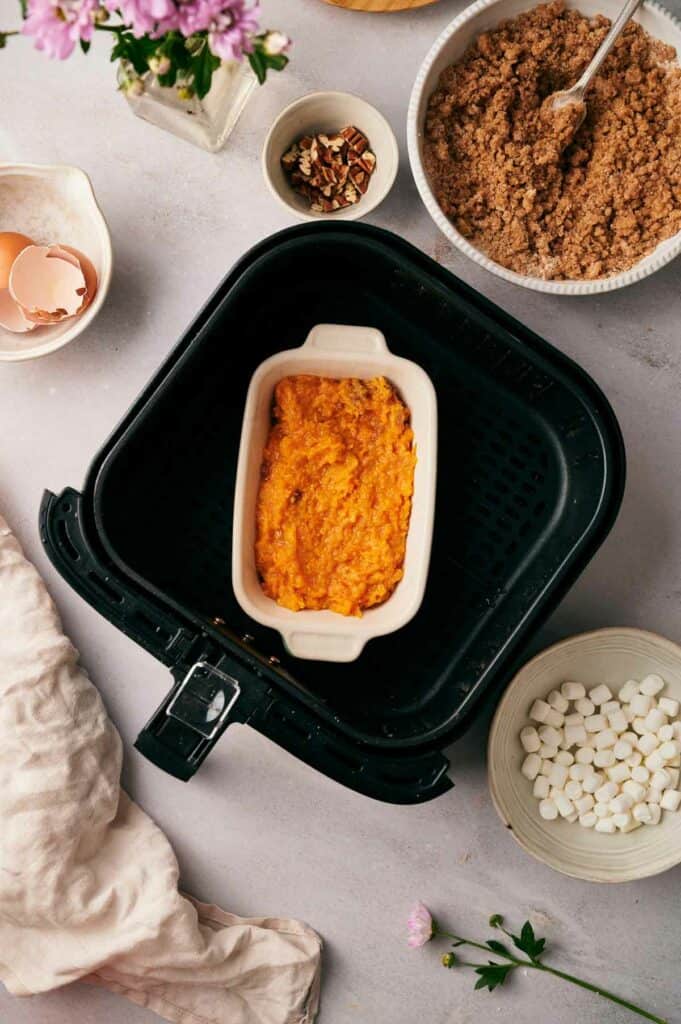 Sweet potato mashed potatoes in an air fryer basket with other ingredients.