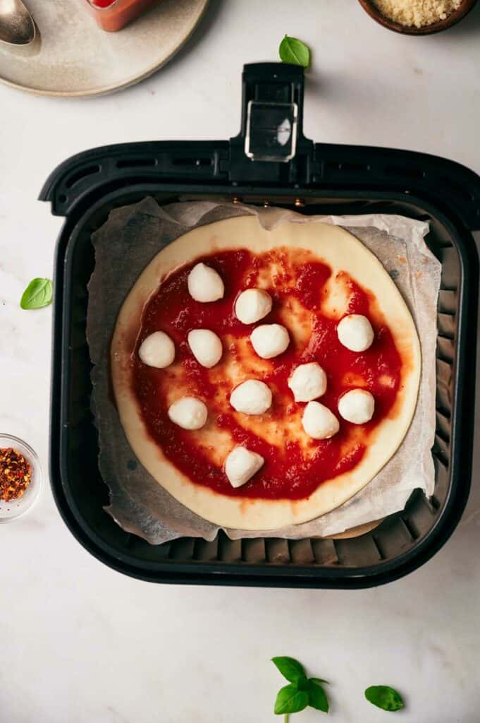 A pizza in an air fryer basket.