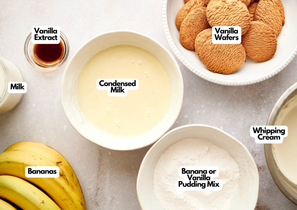 Assorted baking ingredients including milk, vanilla extract, condensed milk, bananas, banana or vanilla pudding mix, whipping cream, and vanilla wafers in bowls on a counter&mdash;perfect for creating Whoopie Pie Halloween Monsters.