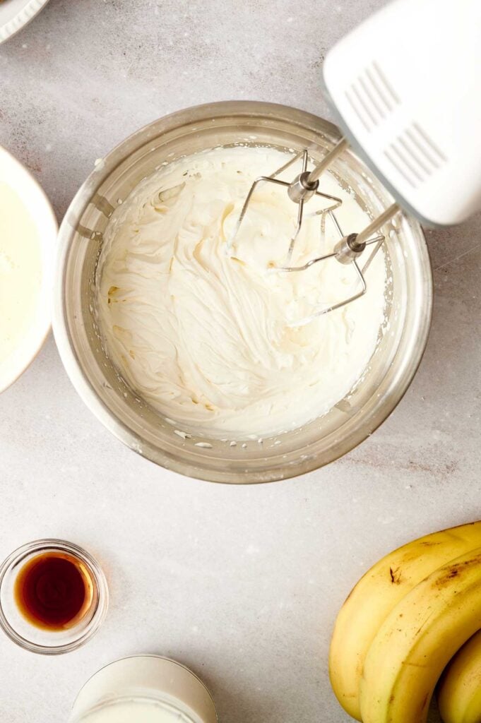Cream cheese mixture whipped to a smooth, fluffy consistency in a metal mixing bowl with a hand mixer