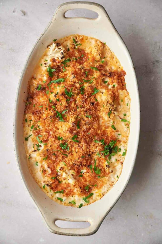 A casserole dish filled with cheese and parsley.
