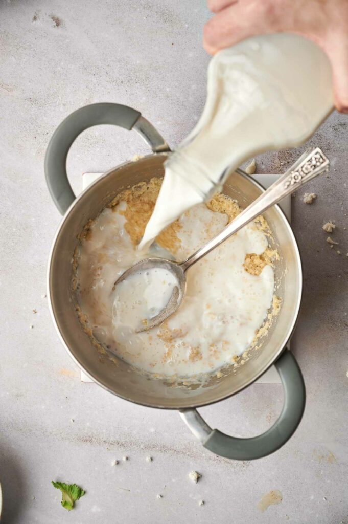 A person pouring milk into a pan.