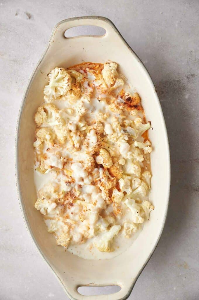 A white dish with cauliflower and cheese in it.
