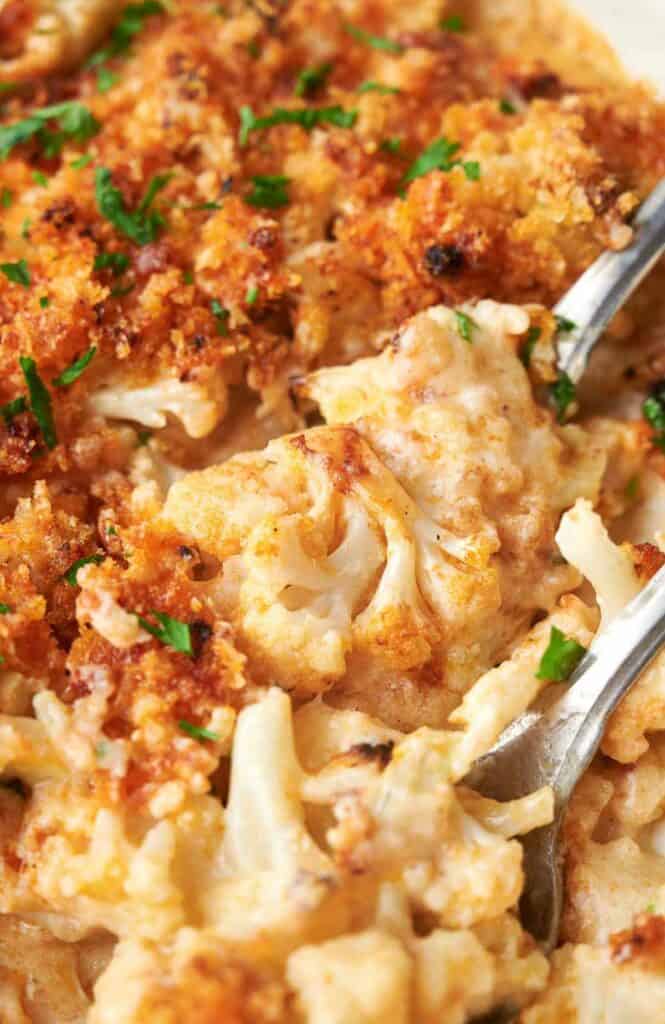 Cheesy cauliflower casserole in a white dish with forks.