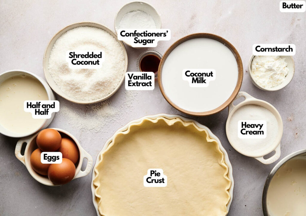 Top-down view of labeled ingredients for coconut cream pie&mdash;pie crust, eggs, half and half, shredded coconut, confectioners' sugar, vanilla extract, coconut milk, butter, cornstarch, and heavy cream&mdash;perfect alongside Witch finger Cookies for a festive treat.