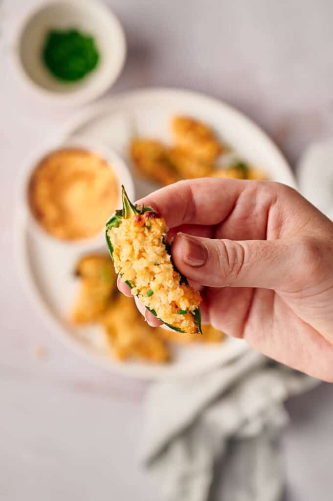 A person holding a plate of Jalapeno poppers.