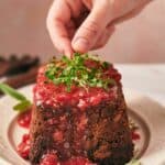A person is placing herbs on a nut roast.