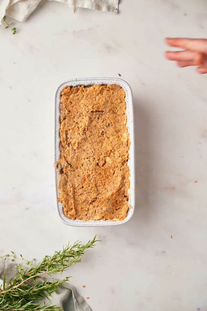 A person reaching for a dish with a sprig of thyme.