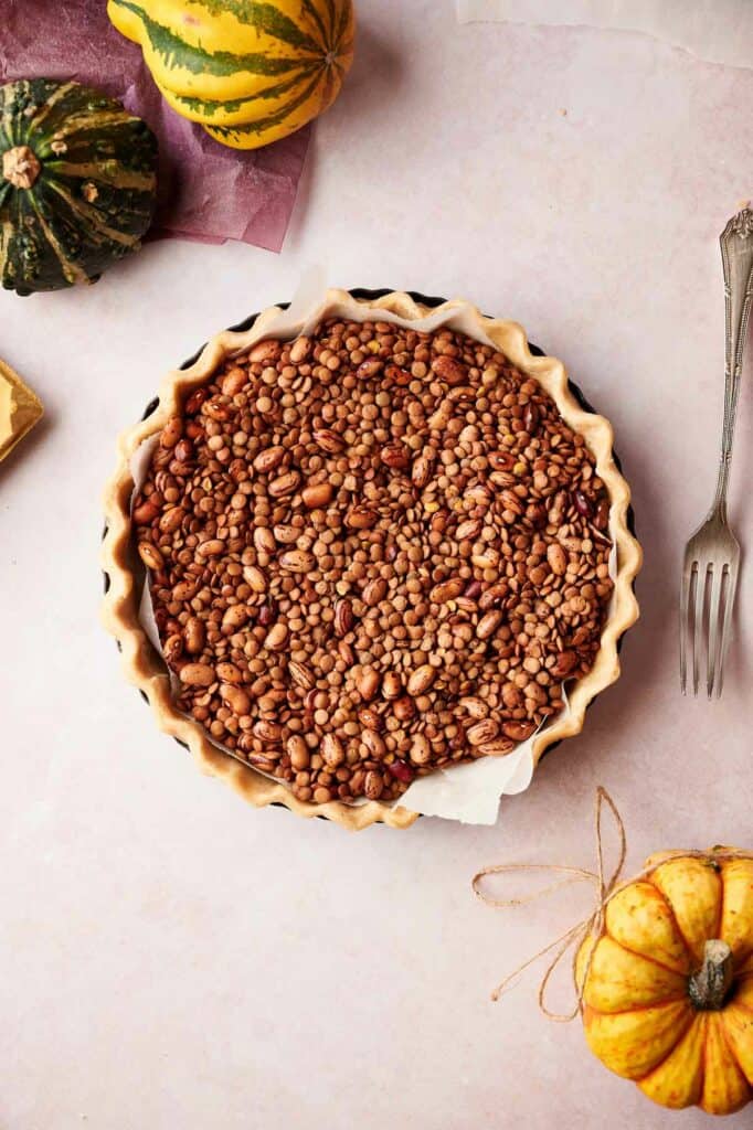 A pie filled with beans and pumpkins on a table.