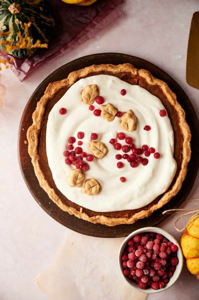 A pumpkin pie with whipped cream and cranberries.