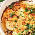 Scalloped potatoes in a white dish with parsley.