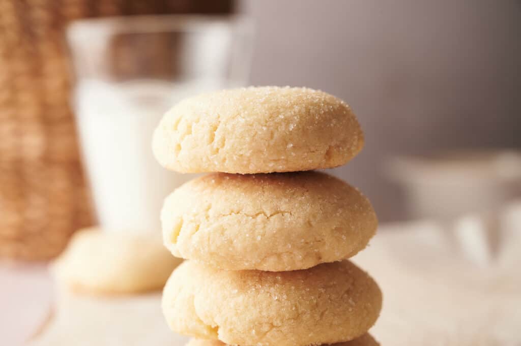 A stack of sugar cookies next to a glass of milk.