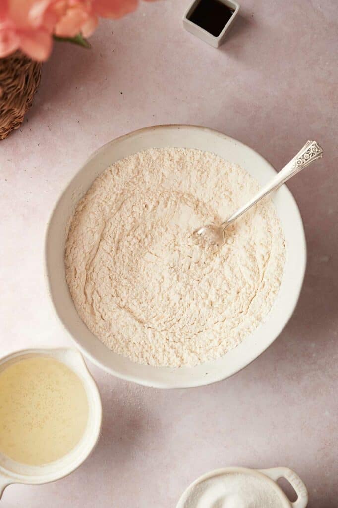 A bowl of flour and a spoon on a table.
