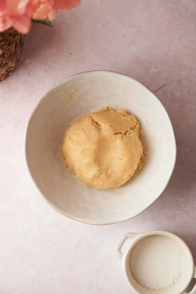 A white bowl with a bowl of sugar and a bowl of flour.