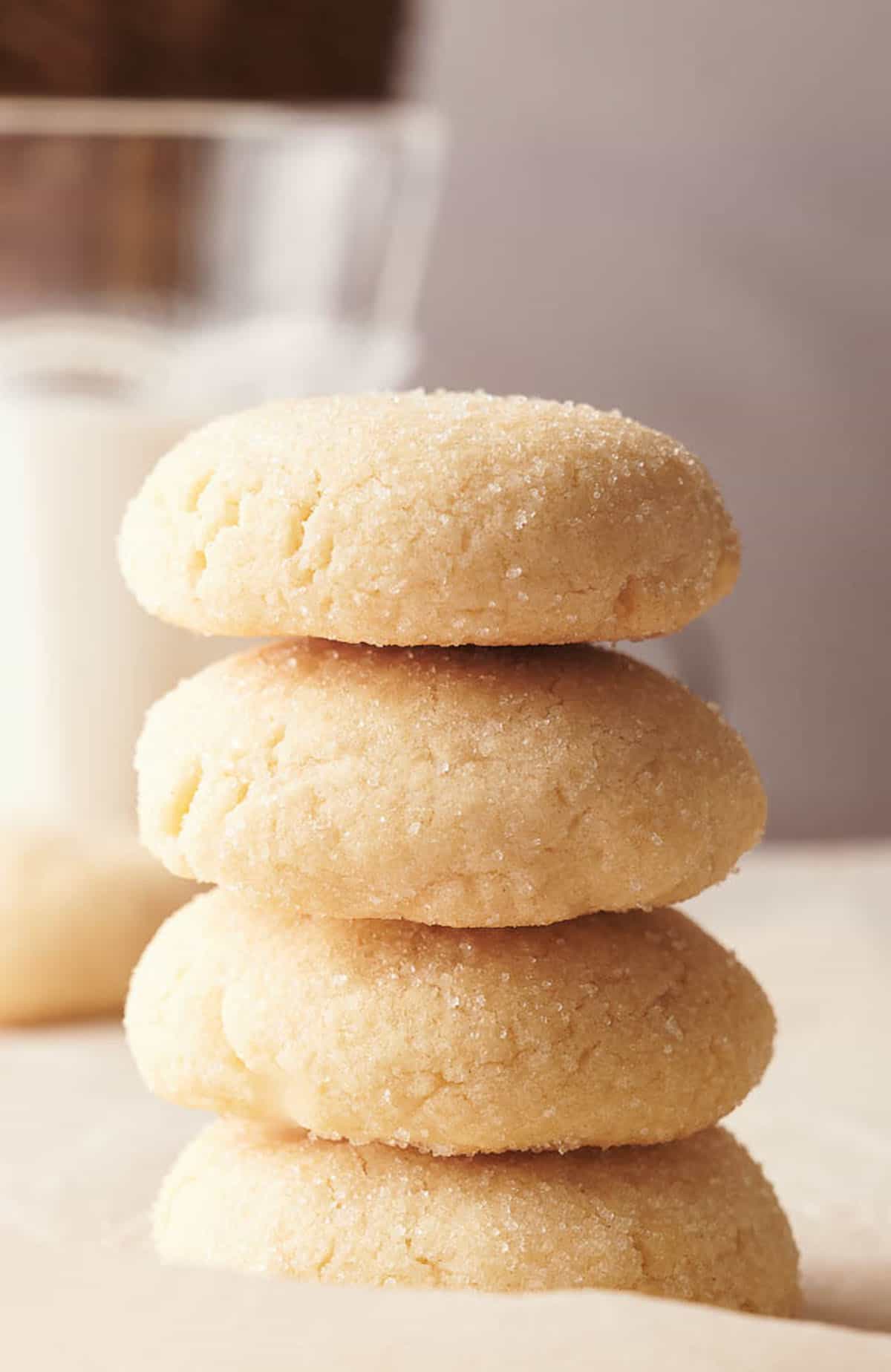 A stack of sugar cookies next to a glass of milk.