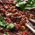 A bowl of vegetarian chili with forks and garnishes.