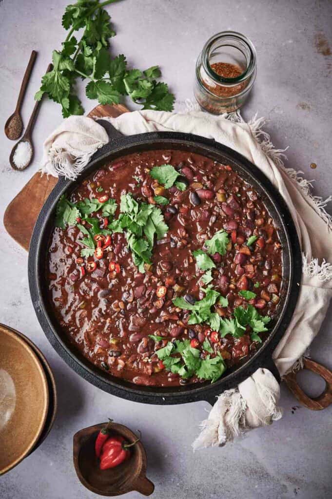 A skillet full of chili on a table.