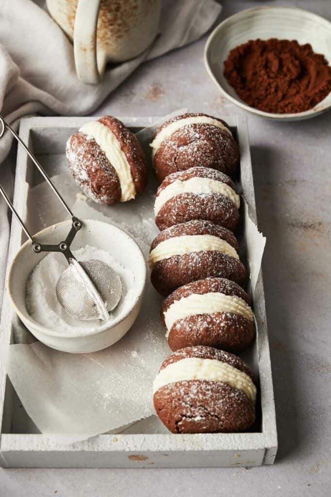 Chocolate whoopie pies on a tray with powdered sugar.