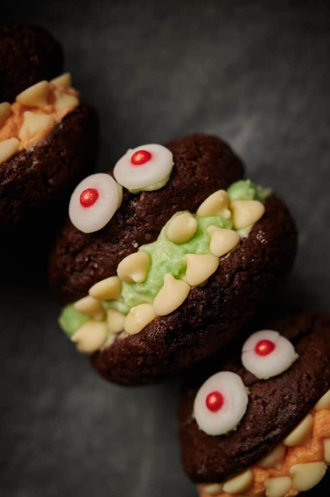 Three chocolate monster whoopie cookies are stacked on top of each other.