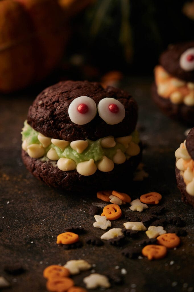 A group of Whoopie pie Halloween monster cookies are arranged on a table.