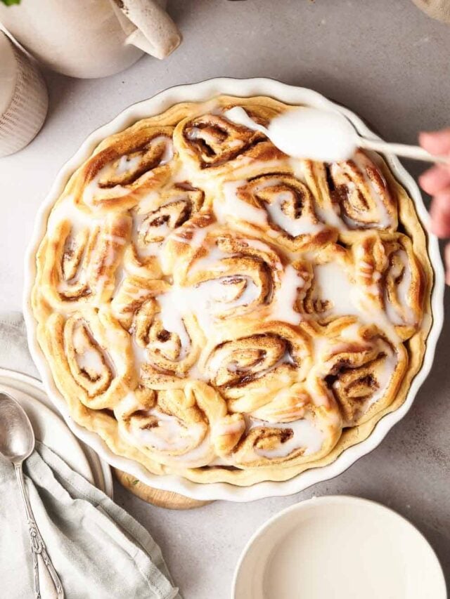 A plate of cinnamon rolls with icing on top.