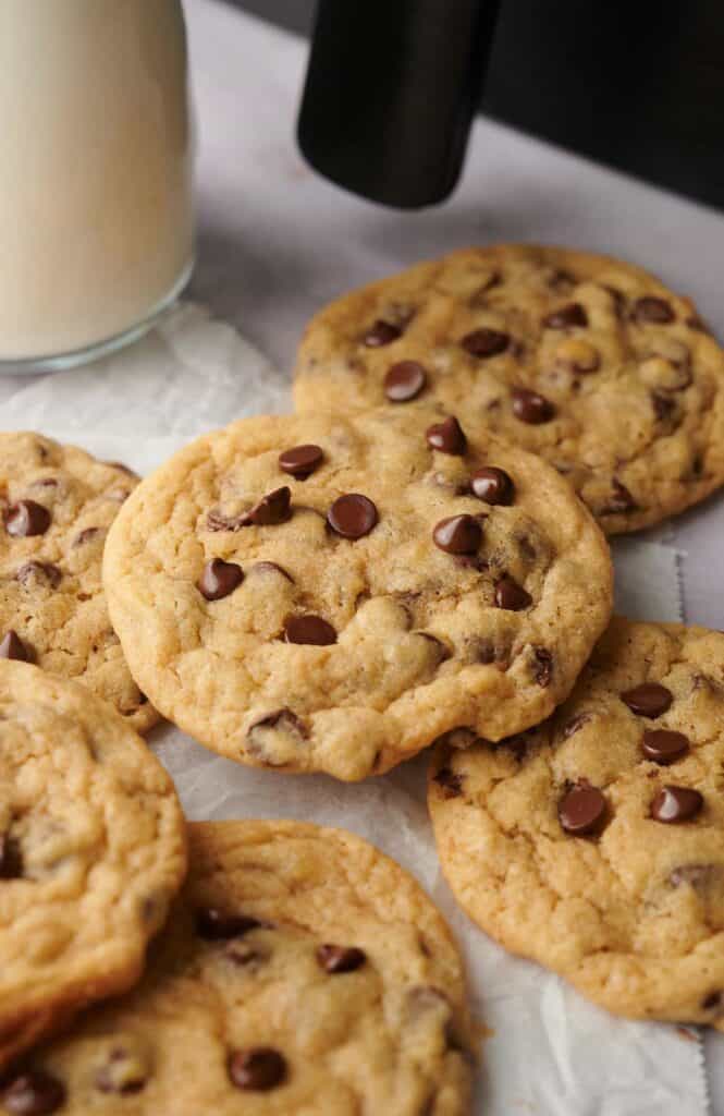 Chocolate chip cookies on a baking sheet next to a glass of milk.