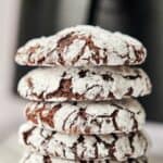 A stack of air fryer chocolate crinkle cookies with powdered sugar.