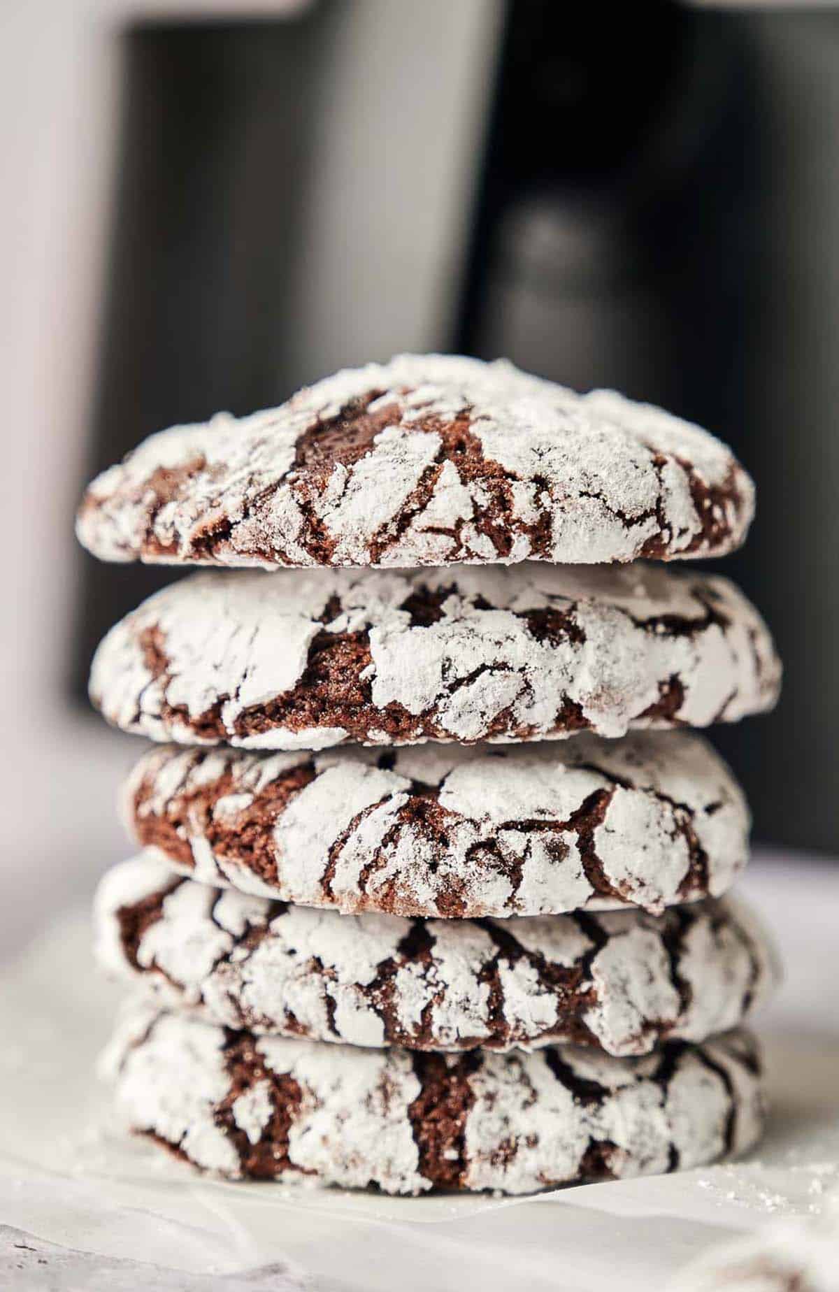 A stack of air fryer chocolate crinkle cookies with powdered sugar.