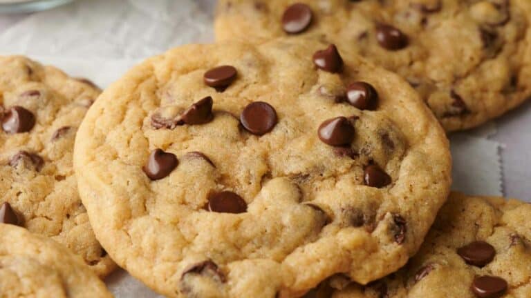 A close up of chocolate chip cookies with a glass of milk.