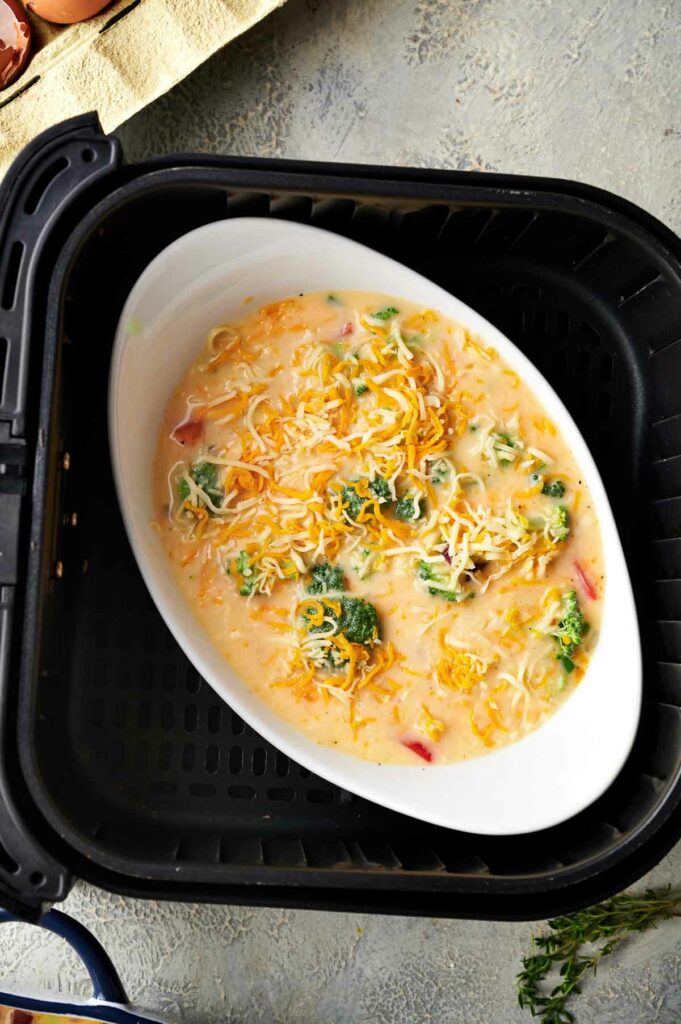 An air fryer filled with egg, broccoli, and cheese casserole.